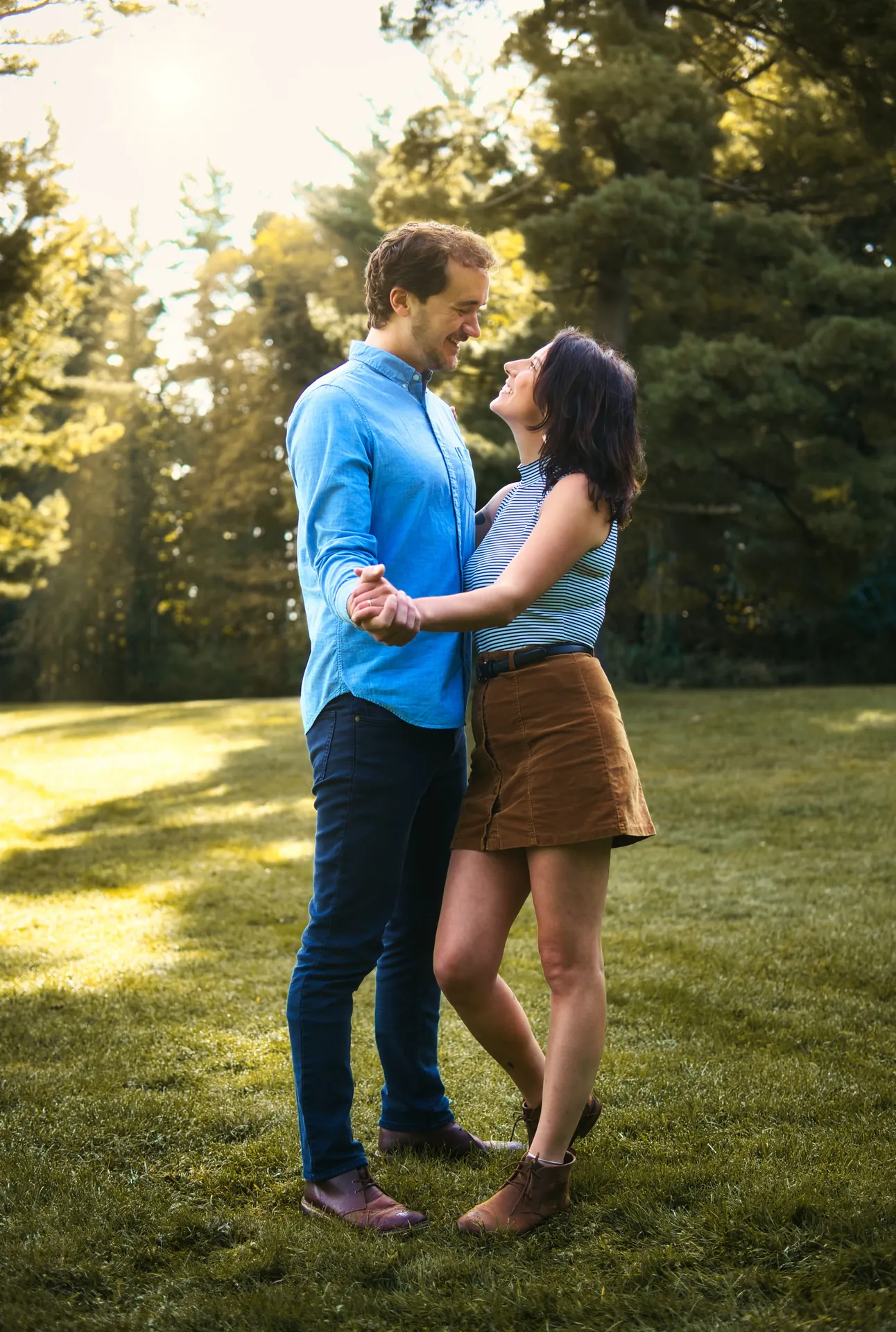 Casal de mãos dadas num parque, com o sol atravessando as árvores