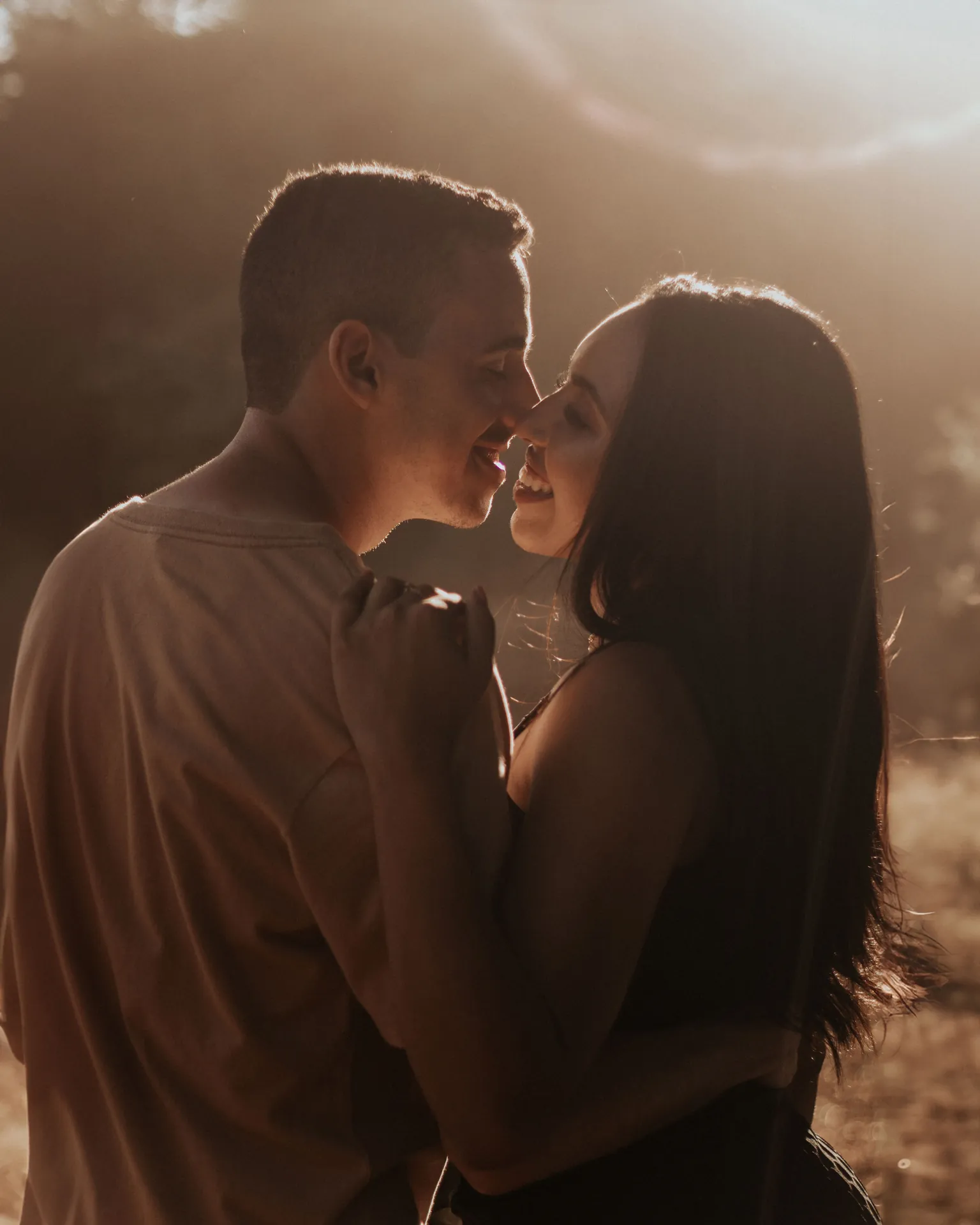 Casal quase se beijando em contraluz dourado no fim de tarde