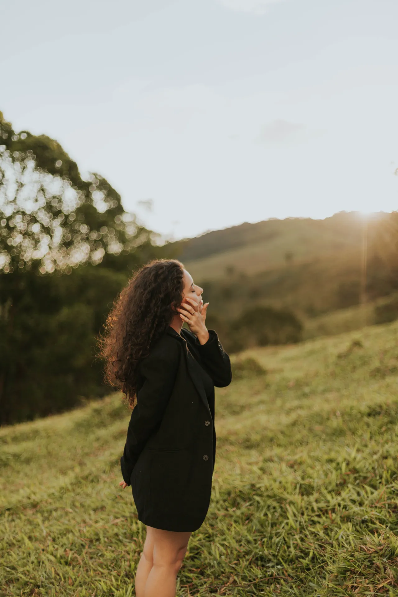 Mulher rindo num campo verde, com montanhas ao fundo