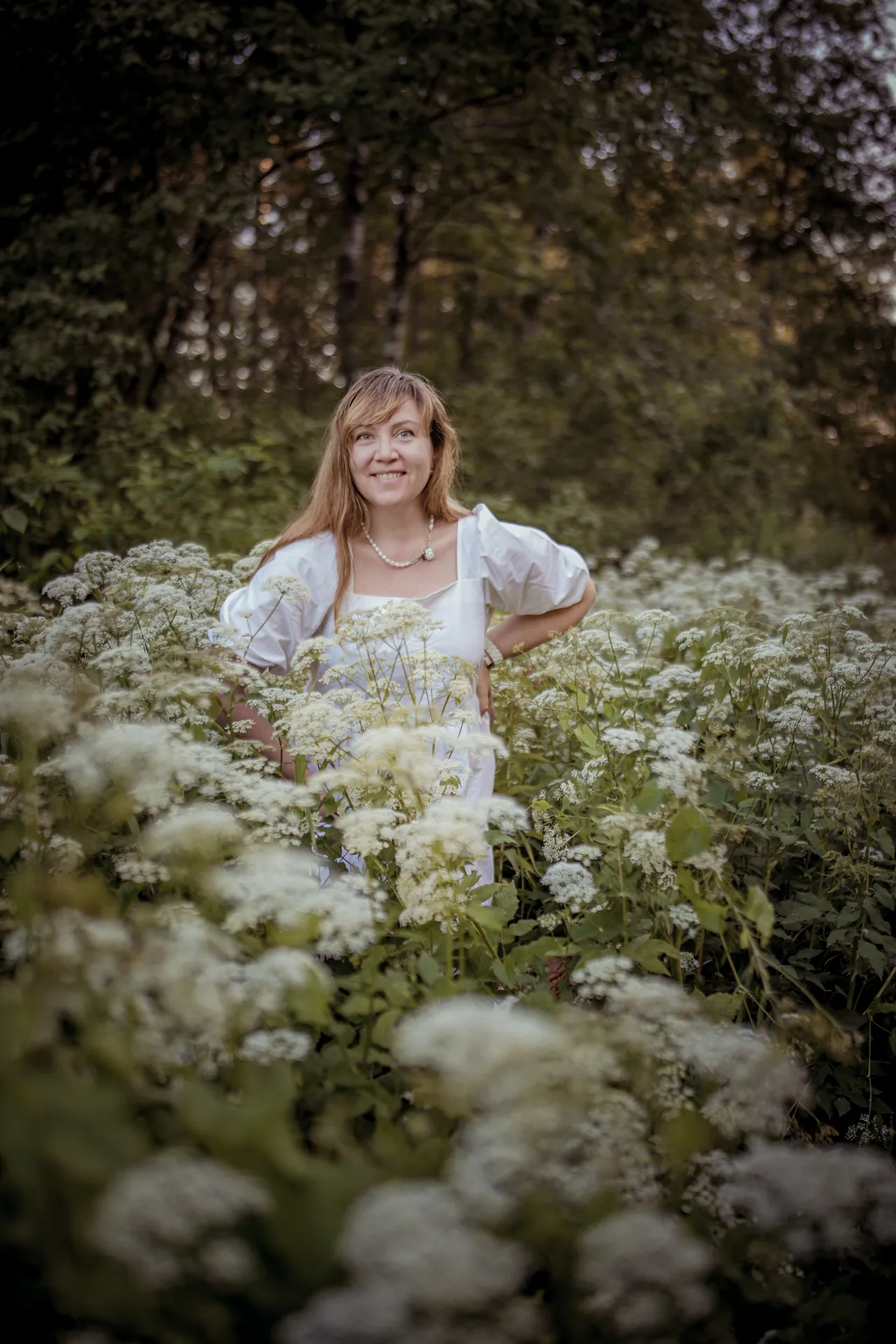 Mulher em pé num campo de flores brancas