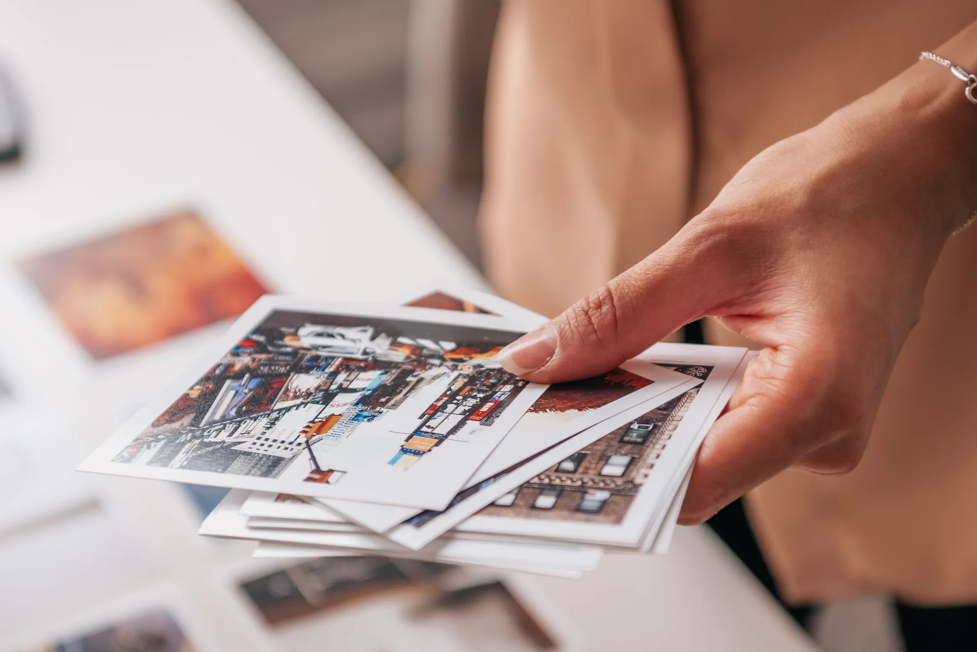 Mãos segurando fotos impressas sobre uma mesa