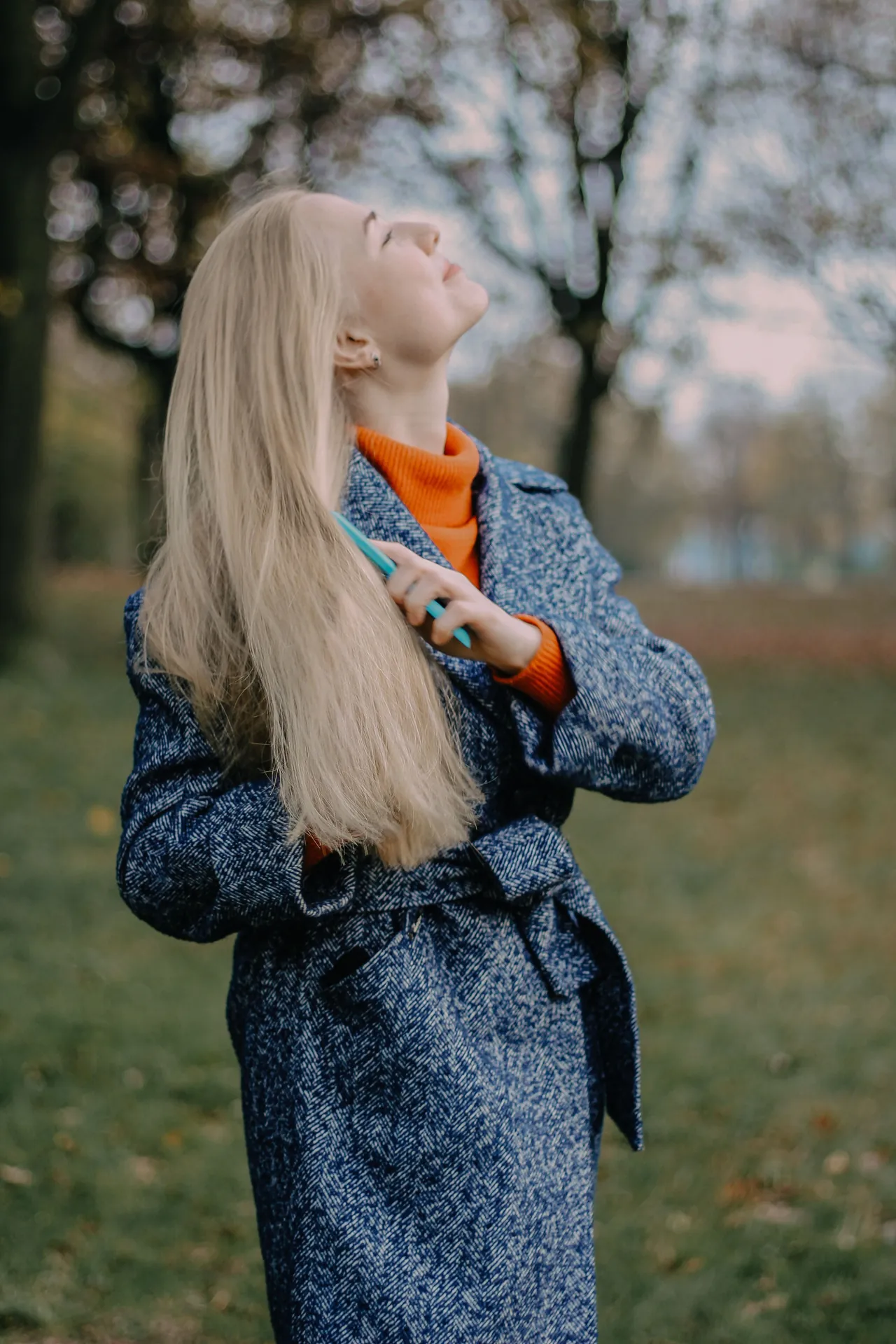 Mulher penteando o cabelo num parque de outono