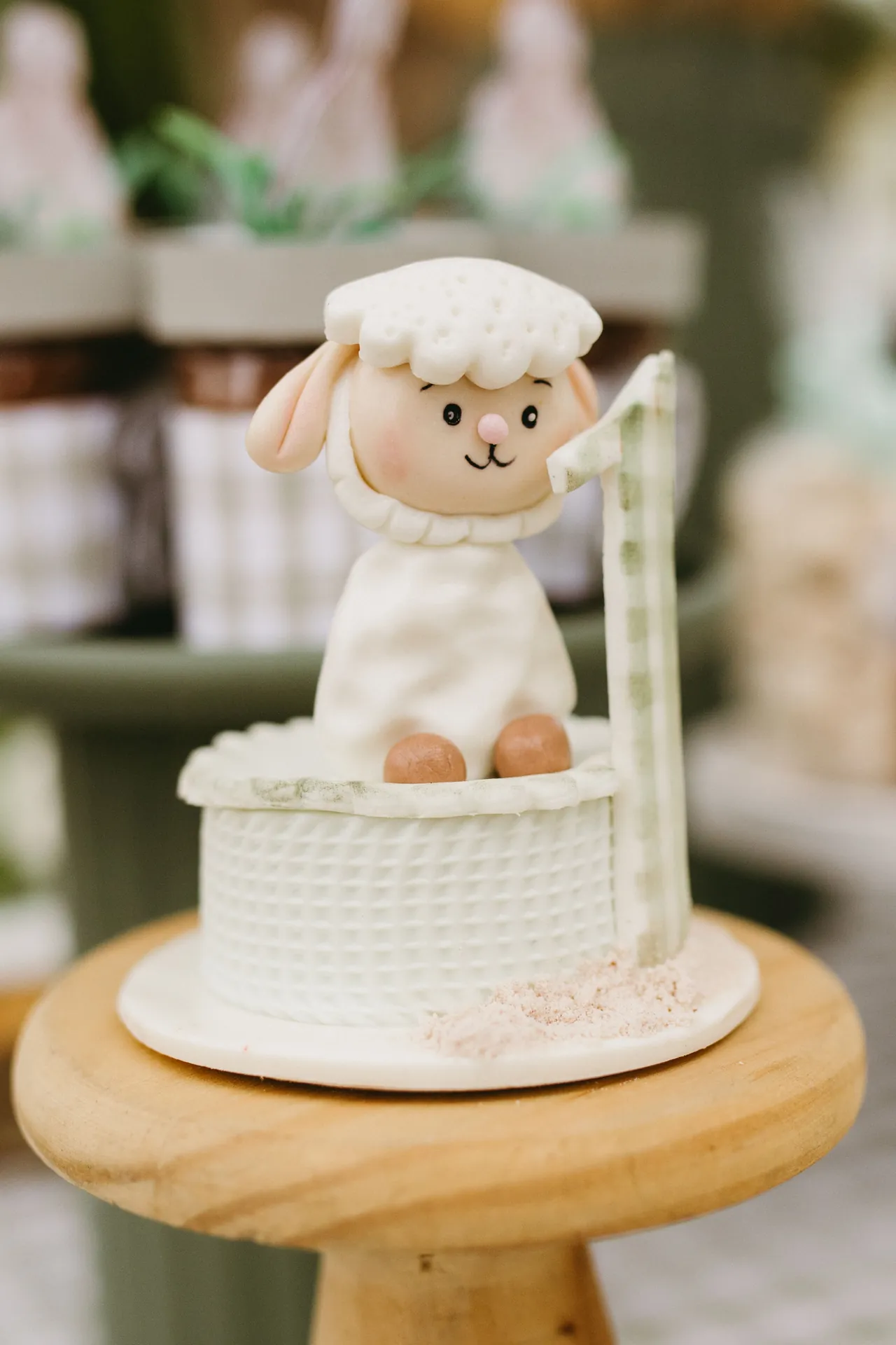 Bolinho branco de primeiro aniversário com uma ovelhinha de açúcar, num apoio de madeira